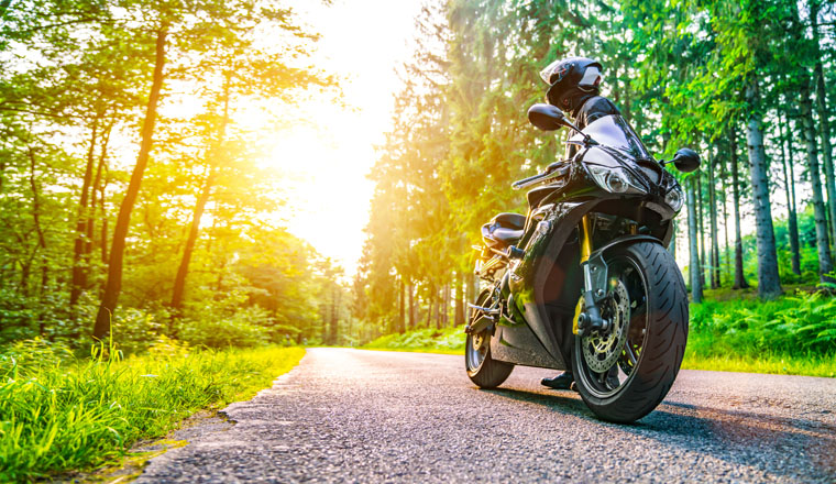 motorbike on the forest road riding. having fun driving the empty road on a motorcycle tour journey. copyspace for your individual text.