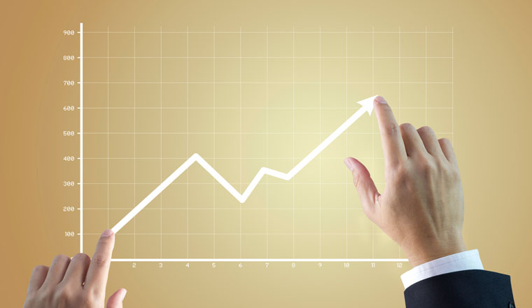 Close up of a businessman’s hands drawing a line graph showing of business growth and success rapidly on golden background.