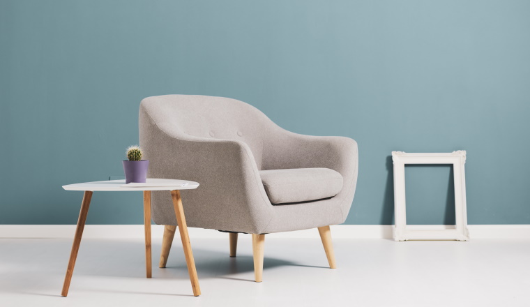 Living room interior with minimalist scandinavian style furnishing and empty frame leaning on the floor