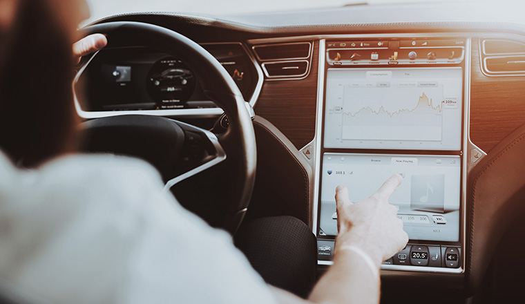 Caucasian Man In The Tesla Car. Front Seat Concept. Innovation Technology. New Generation Electro Hybrid Vehicle. Luxury Design. Futuristic Power. Hands On Display. Behind The Wheel.