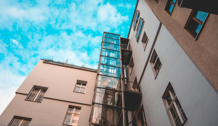 glass elevator at apartment house with fluffy background sky