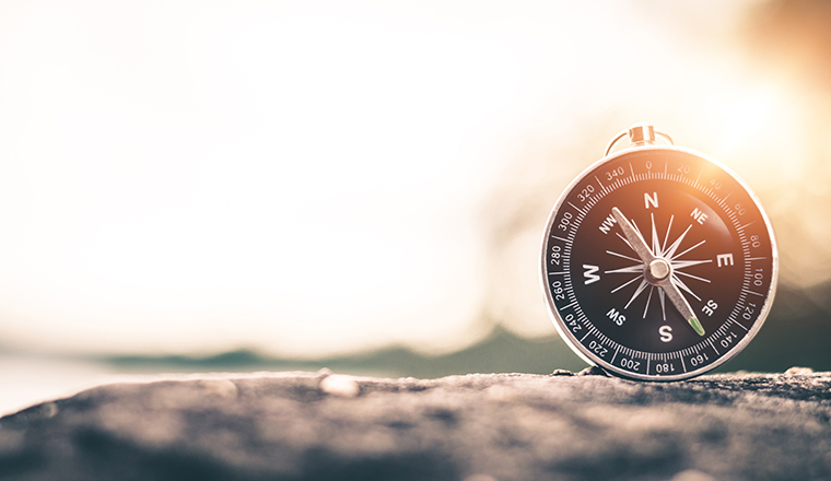 Compass of tourists on mountain at sunset sky.