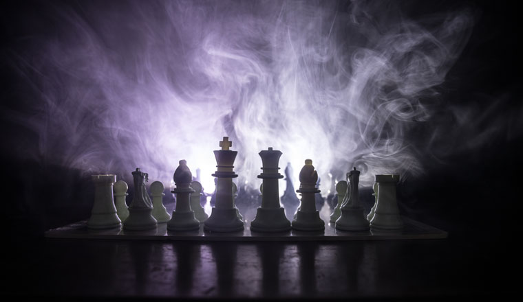 Chess board game concept of business ideas and competition or strategy ideas concept. Chess figures on a dark toned foggy background. Selective focus