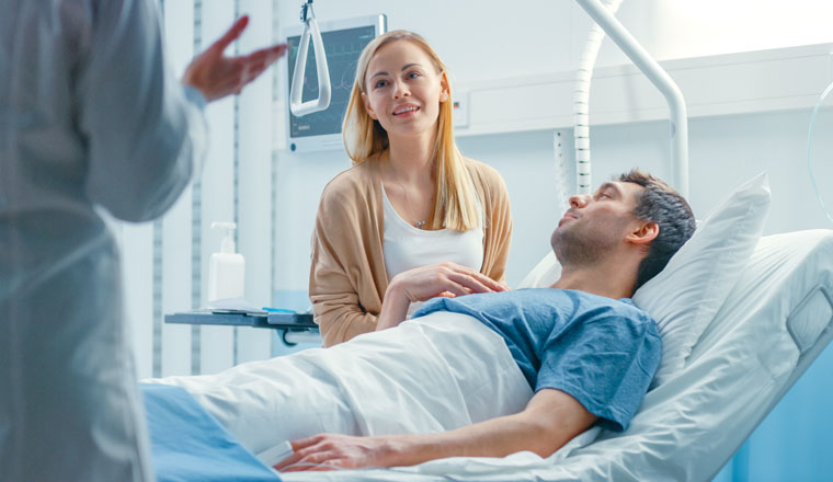 In the Hospital, Patient Lying in Bed, his Wife Sitting Beside, They Listen to Doctor's Explanations. Love and Care Concept.