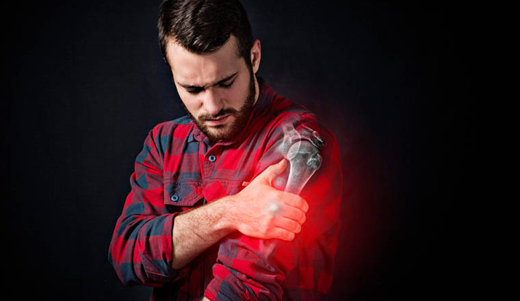 a young man holding onto a sore shoulder against a black background. X-ray