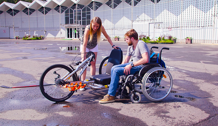 Happy young disable man in wheelchair near hand bike.