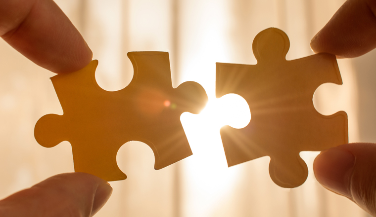 two hands trying to connect couple puzzle piece. with sunset background. symbol of association and connection, business strategy, completing, team support and help concept