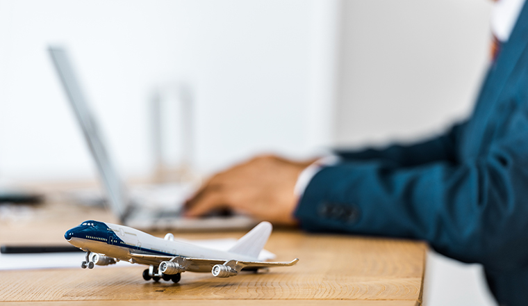 toy airplane at wooden table with office worker using laptop on blurred background 