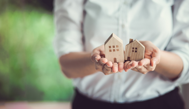 Hand of woman holding a toy house. Home safety , Home care , Home for sale concept.