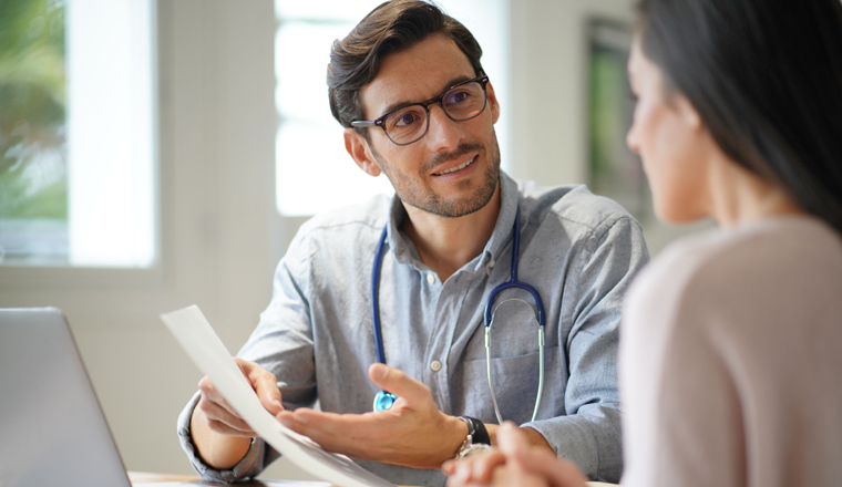  Modern young doctor speaking to patient in office                              