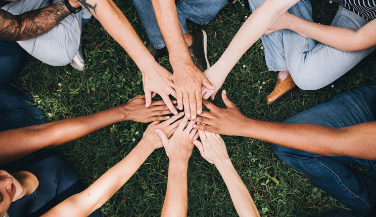 People stacking hands together in the park