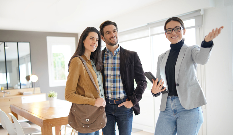 Real estate agent showing modern house to attractive couple