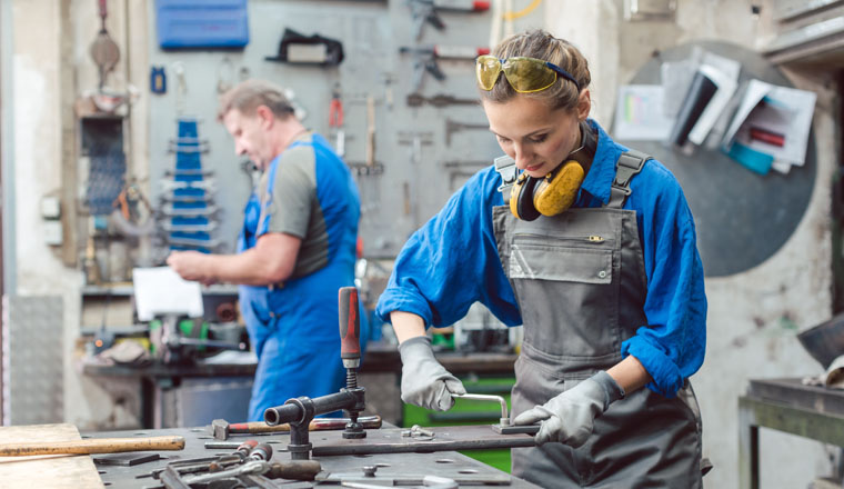 Man and woman working together in metal workshop with their tools