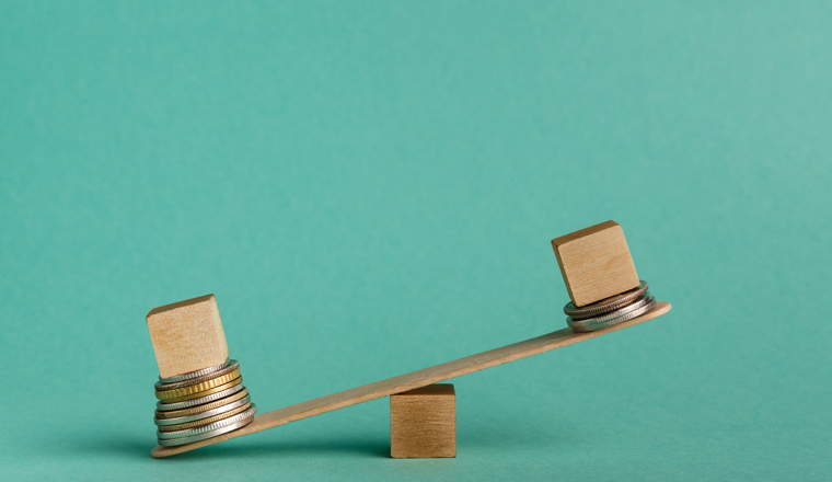 Pay gap and discrimination. Empty wooden cubes on seesaw with different stacks of coins, one outweigh, copy space