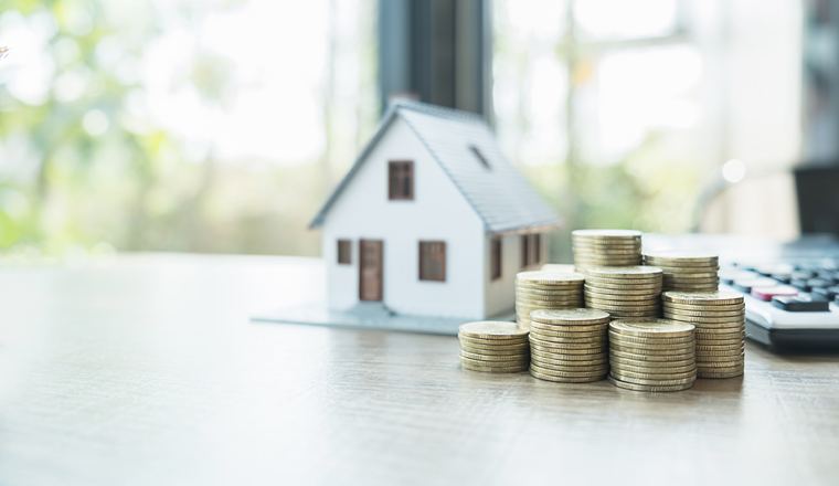 Saving money for house and real estate. Woman hand protecting on stack coins and house model on table.