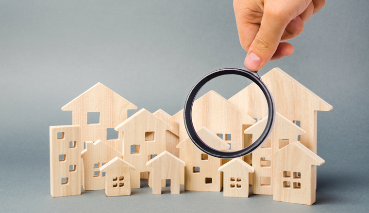 Wooden houses and magnifying glass. Property valuation. Home appraisal. Choice of location for the construction. House searching concept. Search for housing and apartments. Real estate