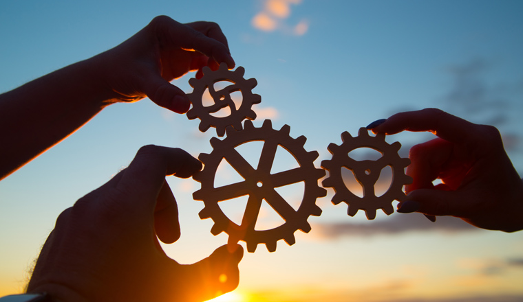 hands of businessmen assemble a puzzle from gears against the sky in the sunset. business concept idea, partnership, innovation, teamwork, cooperation