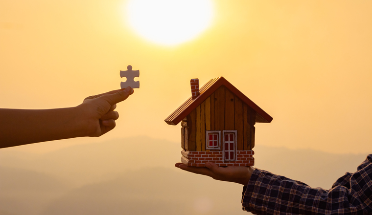 property service concept, Human hands holding house model and piece jigsaw puzzle at sunset