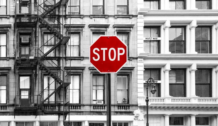 Red stop sign against background of old black and white buildings in the SoHo neighborhood of Manhattan, New York City NYC