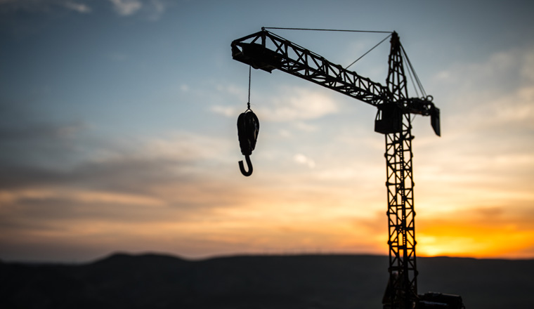 Abstract Industrial background with construction crane silhouette over amazing sunset sky. Tower crane against the evening sky. Industrial skyline. Selective focus