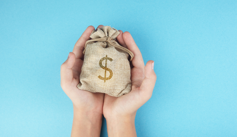 Women hold a money bag on light blue background, Saving money for future investment concept.