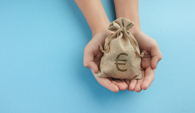 Women hold a money bag on light blue background, Saving money for future investment concept.