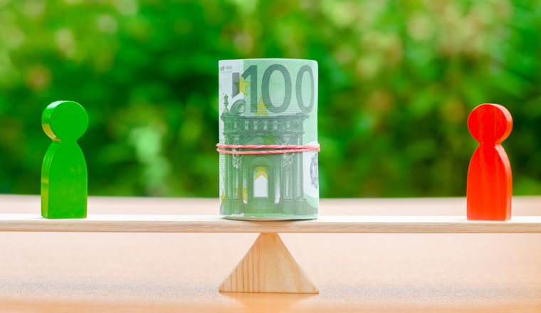 Wooden figures of people on scales and euro banknotes between them. The concept of separation of money. Property division. Divorce and legal services. Business conflict. Financial dispute