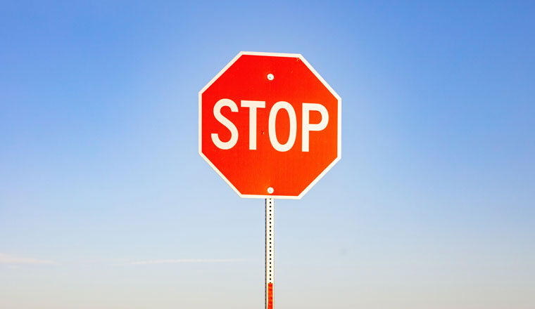 Stop road sign against blue sky background. Sunny spring day