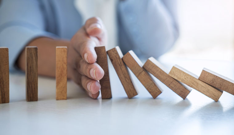 Risk and Strategy in Business, Image of hand stopping falling collapse wooden block dominoes effect from continuous toppled block, prevention and development to stability.