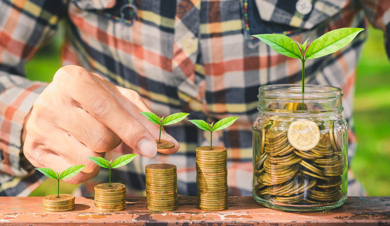 businessman putting green leaf coin on stack save money growing in to glass jar on wood table outdoor. business financial banking saving concept. investment profit income. marketing startup success.