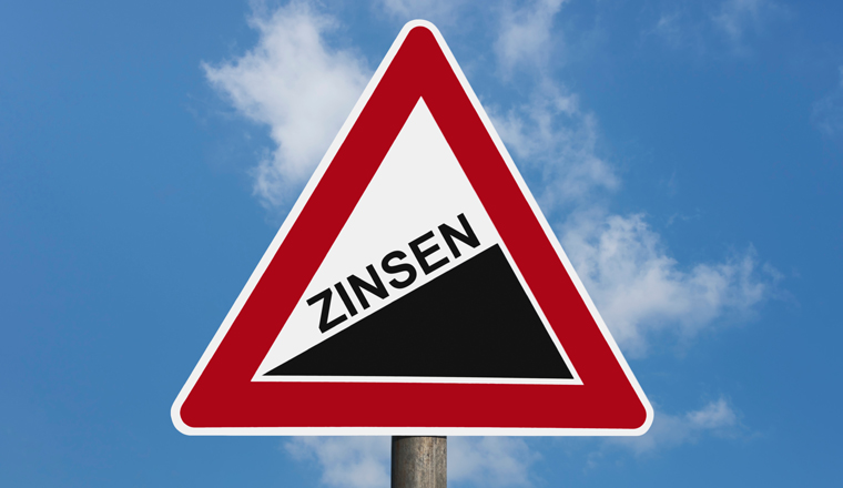 Detailansicht eines Gefahrenzeichens "Steigung" mit der Beschriftung Zinsen | Detail photo of a danger sign "Upward gradient" with the german inscription interest rate