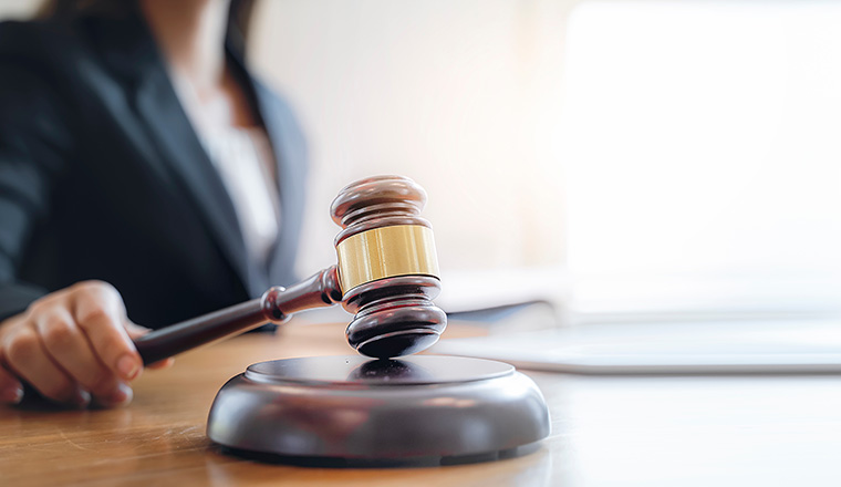 Woman judge hand holding gavel to bang on sounding block in the court room.