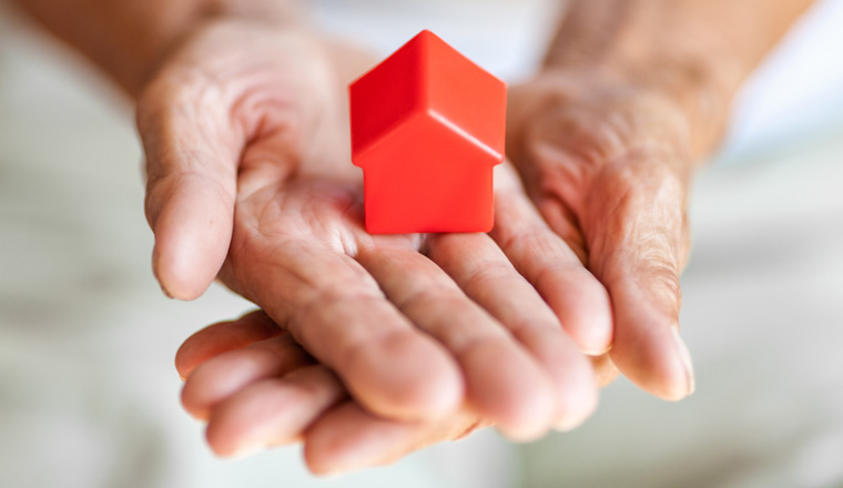 Elderly woman holding a small house in her hands