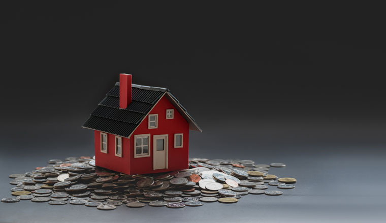 Real estate and property investment concept : small house model on stack of coins with black background 