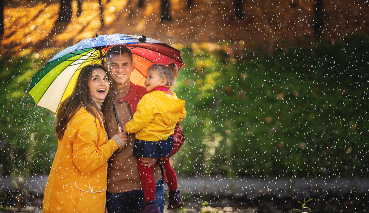 Happy funny family with colourful umbrella under the autumn rain.