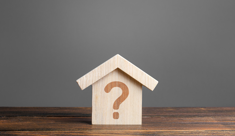 Question mark on a wooden house. Solving housing problems, deciding to buy or rent real estate. Search for options, the choice of accommodation between apartment and house. Cost estimate