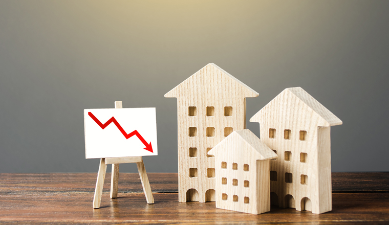 Wooden houses residential buildings and an easel with a red down arrow. Fall of real estate market. Value cost decrease. Bad liquidity attractiveness. Cheap rent. Reduced demand, recession. Low sales