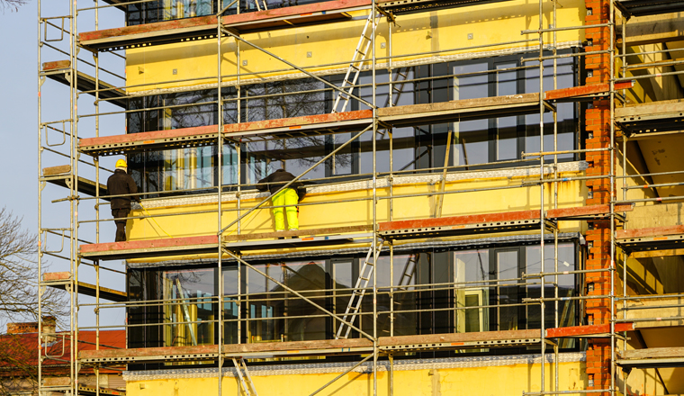 scaffolding arround the house to install thermal insulation of the apartment building facade, blue sky background