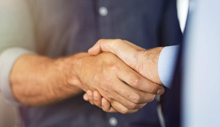 Close up of friendly handshake of business people. Business partners signing deal with handshake at office. Negotiation meeting for a successful merger, business agreeement.