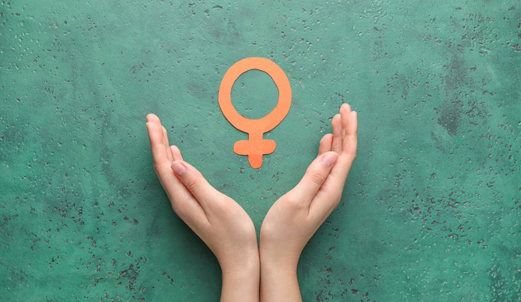 Female hands with symbol of woman on color background. Concept of feminism