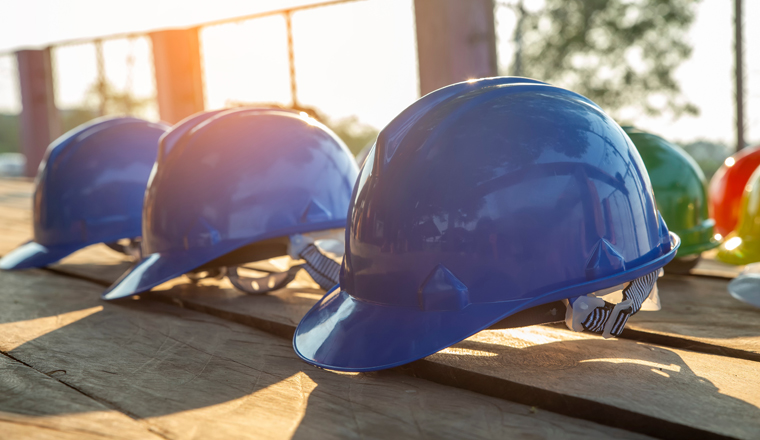 Safety helmet (hard hat) for safety and health officer,engineer or architect place on old wooden floor.Blue safety hat (helmet) in construction site.Safety equipment concept.