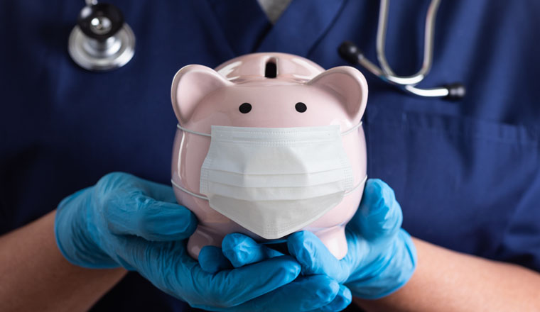 Doctor or Nurse Wearing Surgical Gloves Holding Piggy Bank Wearing Medical Face Mask.