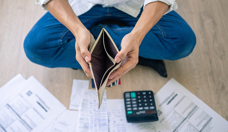 A businessman who is sitting on the floor of the house opening the wallet but have to pay debt Calculation of large amounts of expenses. Debt concepts