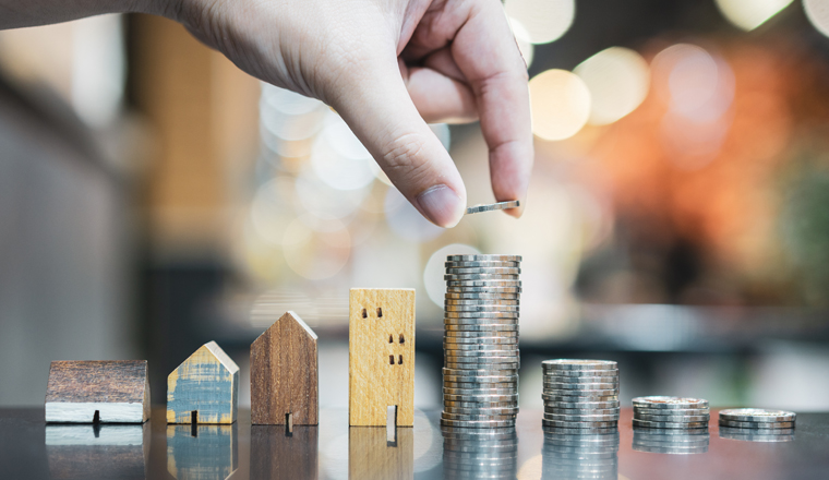 Hand choosing row of coin money on wood table and mini wood house, selective focus, Planning to buy property. Choose what's the best. A symbol for construction ,ecology, loan concepts