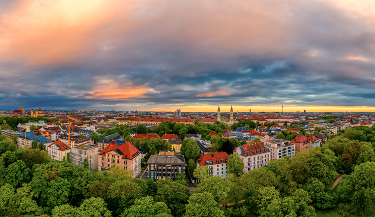 The view at Munich in bavaria from a drone, an panoramic aerial over a park, houses and the frauenkirche in the historical centre of the bavarian capital.