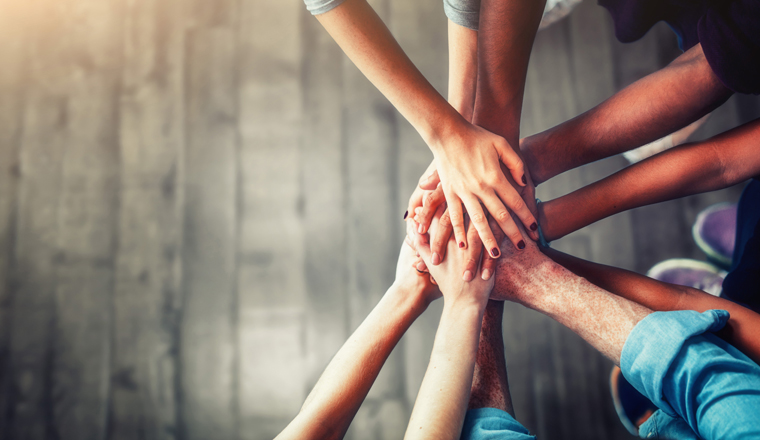 Close up top view of young business people putting their hands together. Stack of hands. Unity and teamwork concept. Left copy-space.