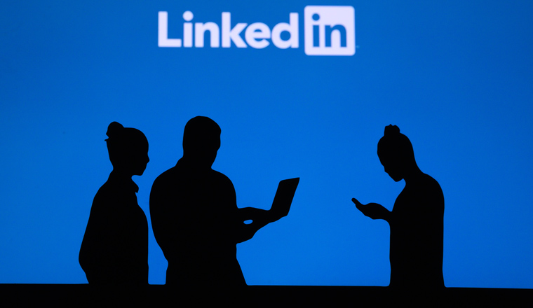 NEW YORK, USA, 25. MAY 2020: Linkedin business and employment-oriented online service Group of business people chat on mobile phone and laptop. Company logo on screen in background