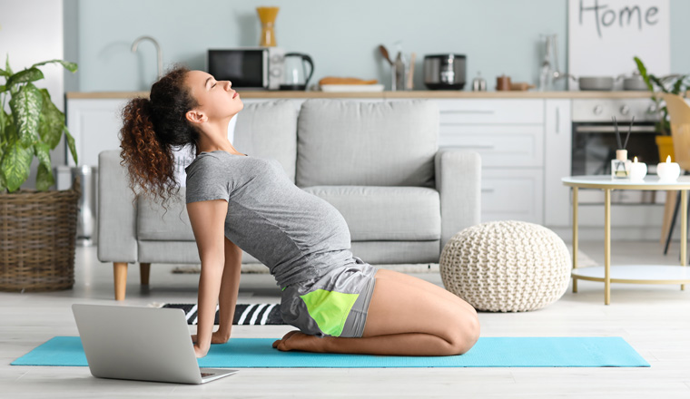 Young pregnant woman practicing yoga at home