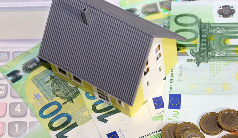 Symbolbild für Immobilienpreise: Modelhaus, Euronoten und Münzen