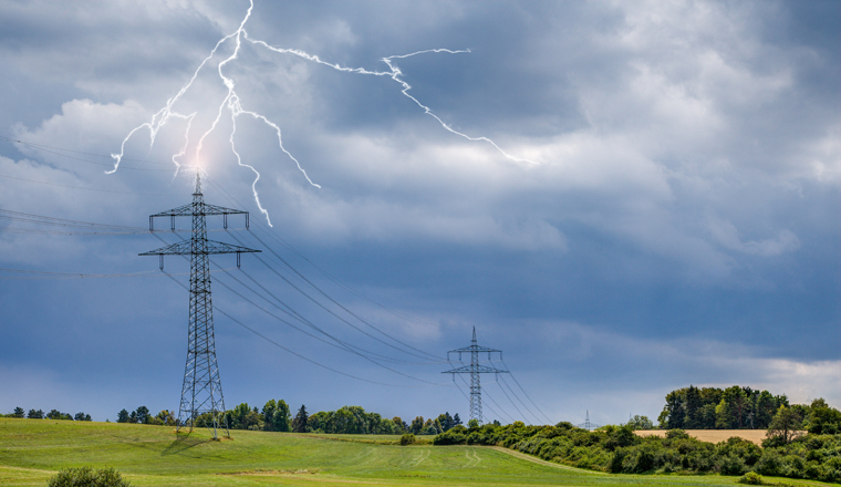 On the sultry, hot summer day, looming storm clouds appear in the sky on the upper Au area near the small town of Trossingen and lightning strikes the high-voltage pylon.